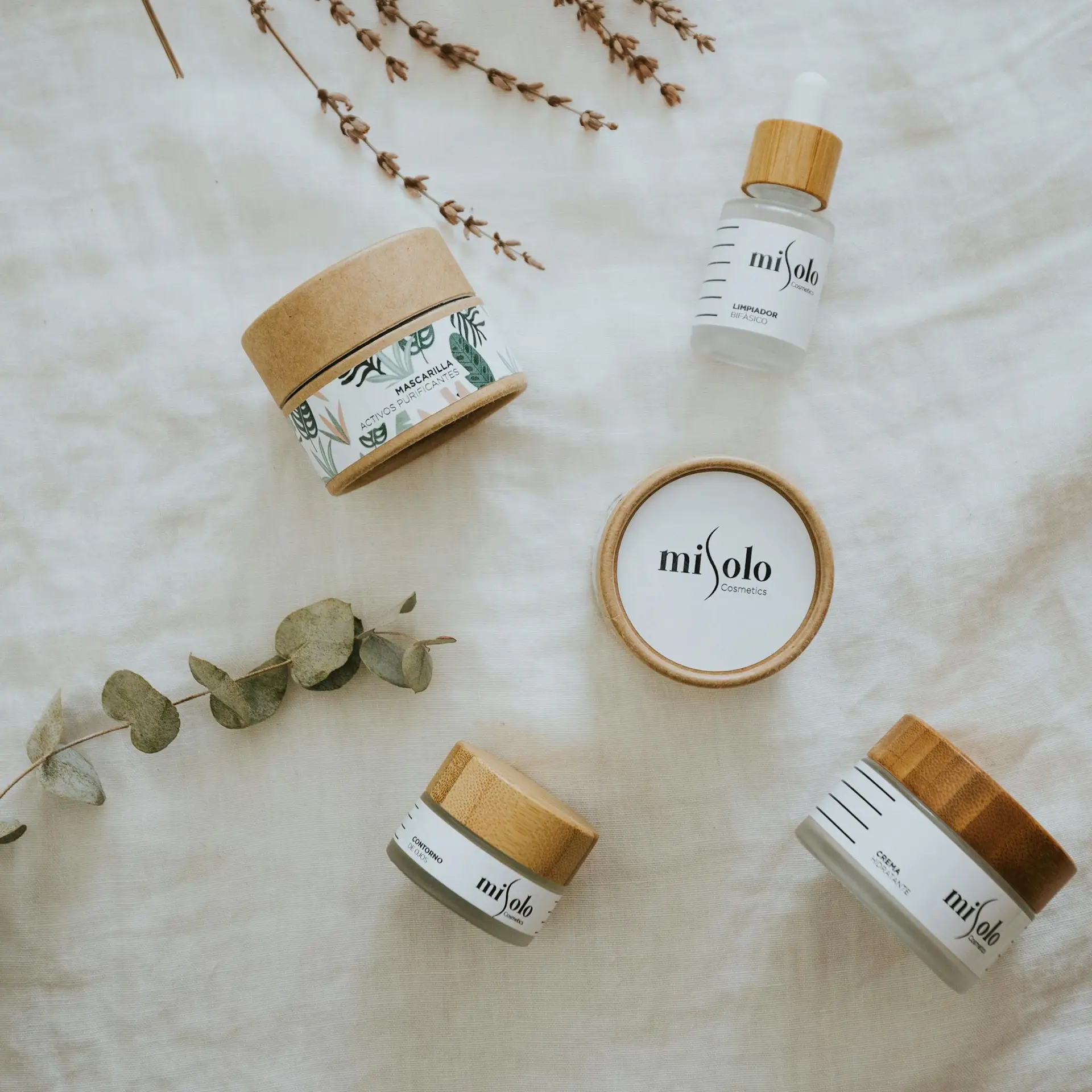 A flatlay of eco-friendly skincare products with natural packaging on a linen cloth backdrop.