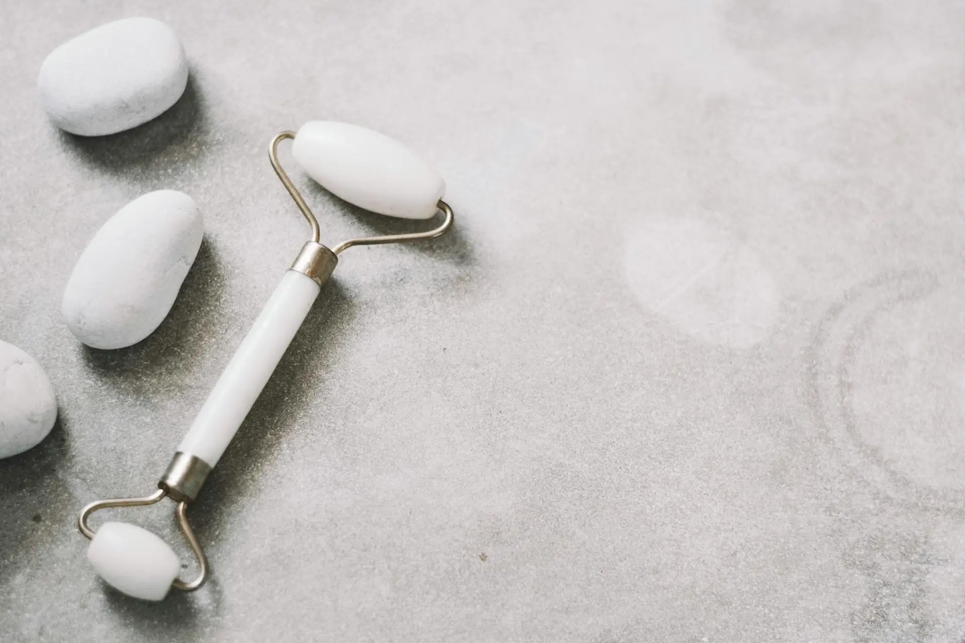 A jade roller and stones on a soft neutral background, ideal for skincare themes.