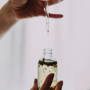Close-up of hands using a dropper with an essential oil bottle, perfect for wellness themes.