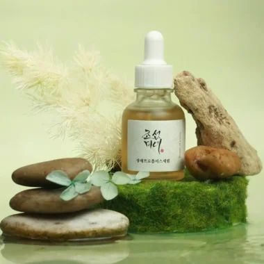 Serum bottle with natural elements and stones on a green background.