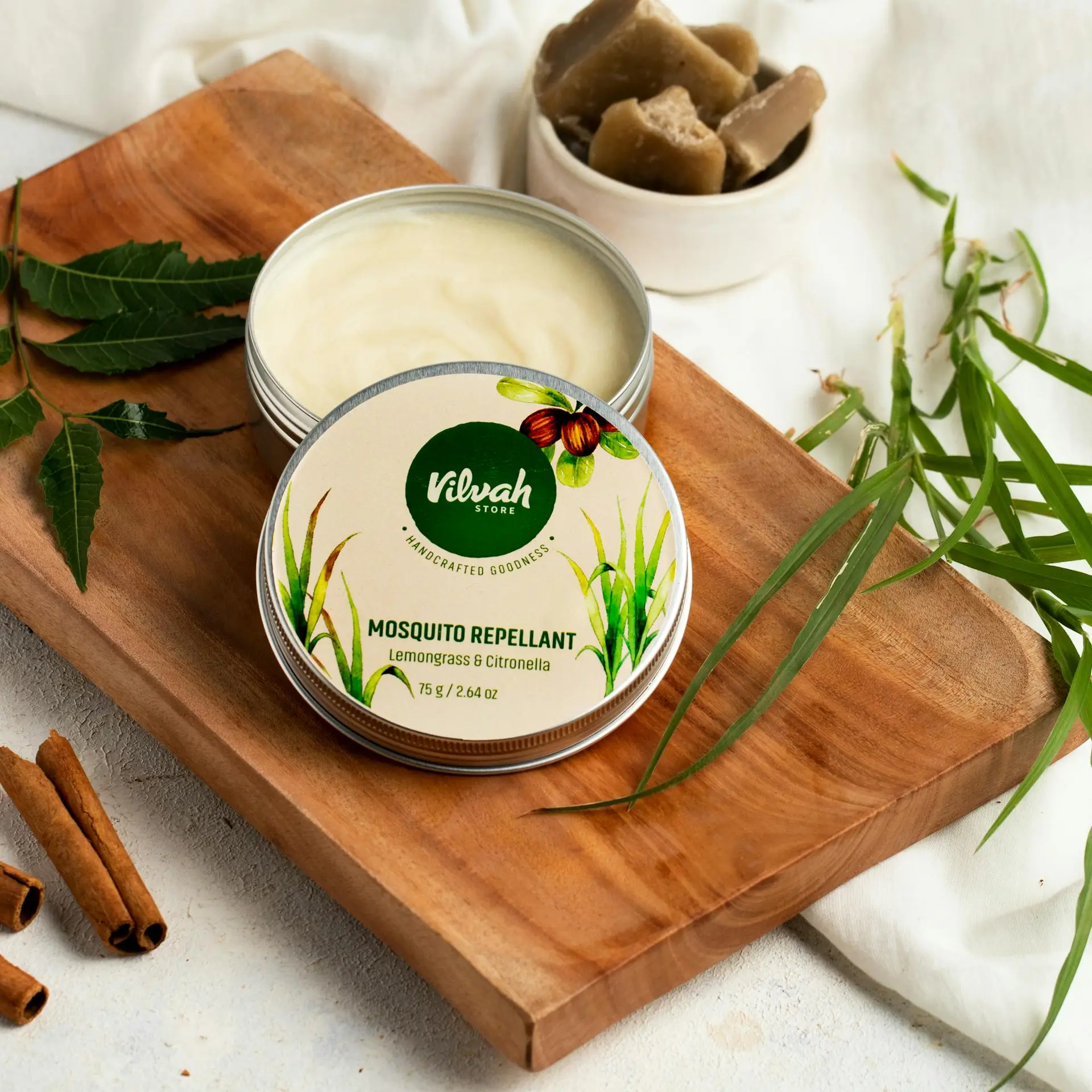 Top view of Vilvah's lemongrass & citronella mosquito repellent in a tin on a wooden board.